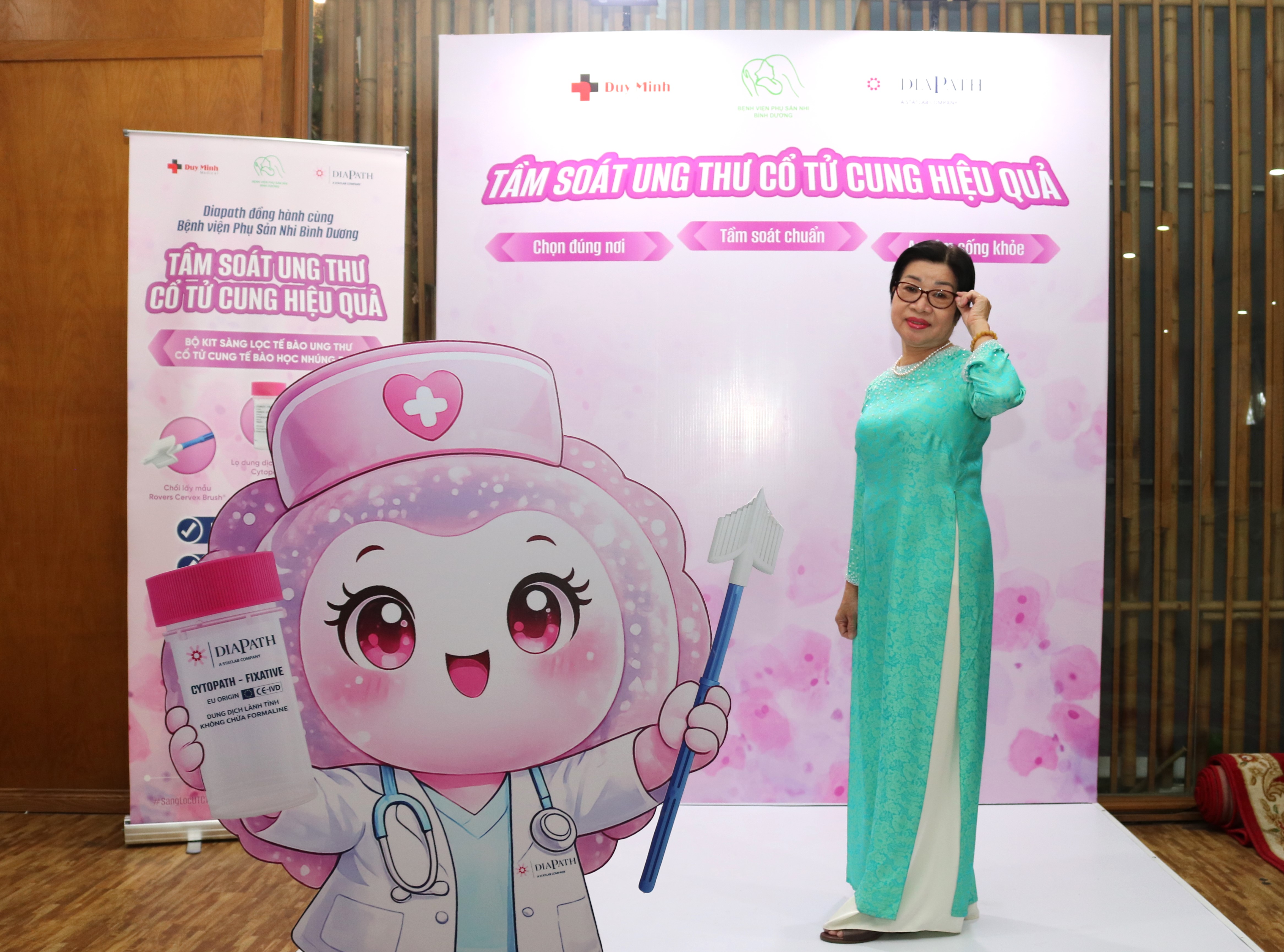 Đại biểu mặc áo dài xanh chụp ảnh tại gian tầm soát ung thư cổ tử cung của Duy Minh