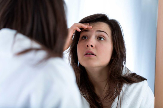 Cô gái đặt tay lên trán vì chóng mặt, mệt mỏi