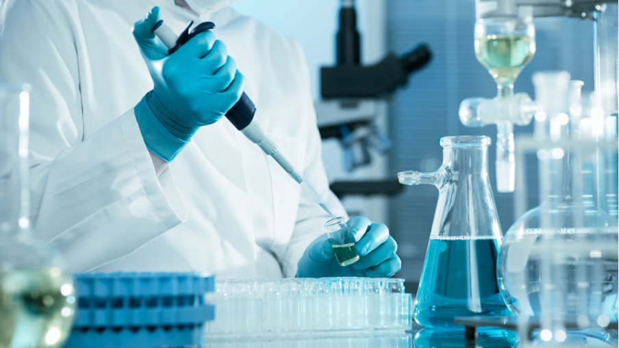 Kỹ thuật viên dùng pipet thao tác với dụng cụ thủy tinh trong phòng xét nghiệm
